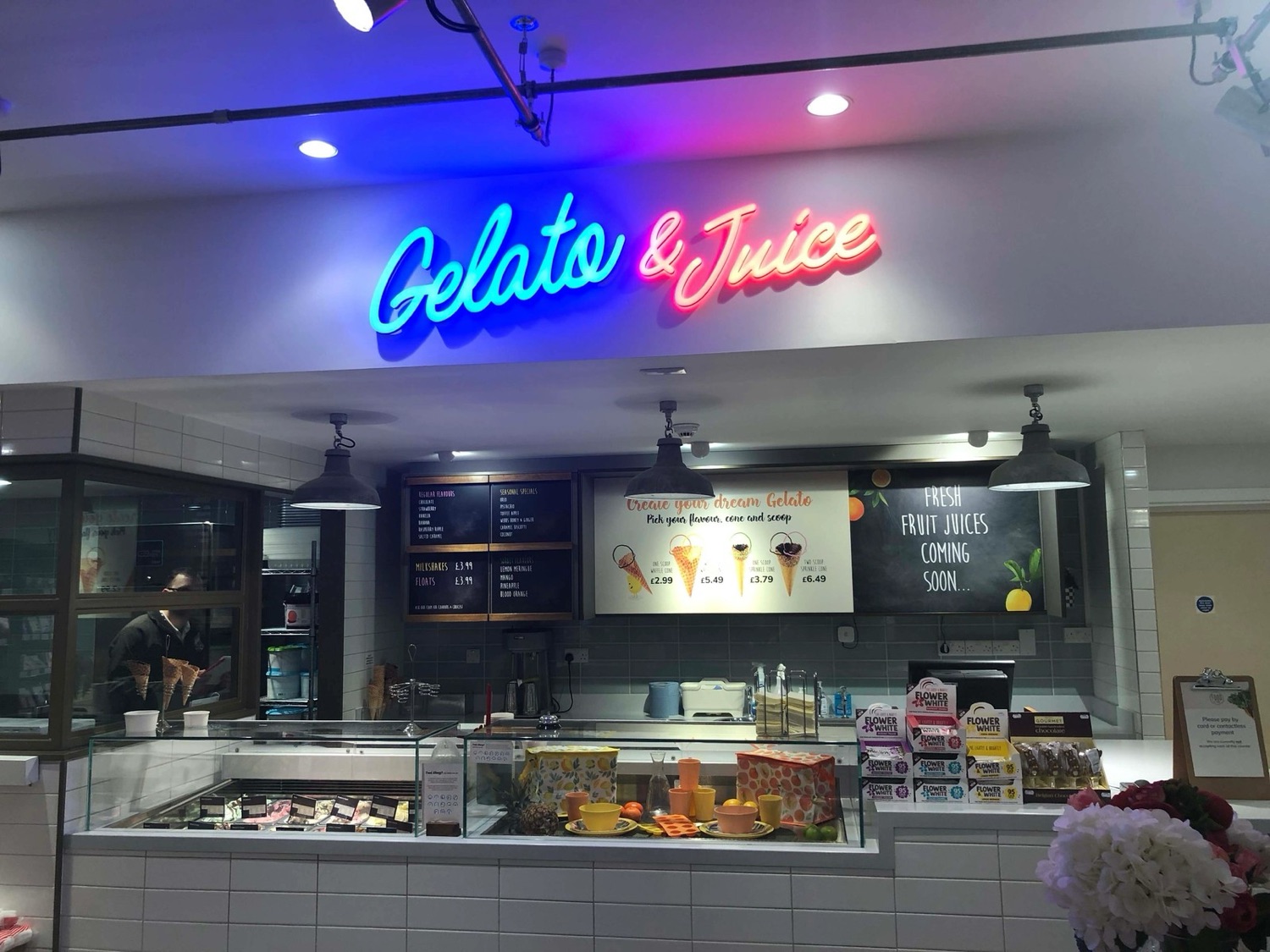 Illuminated 'Gelato & Juice' sign above a food counter
